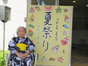 「夏祭り」の看板の前で記念撮影をする利用者さん